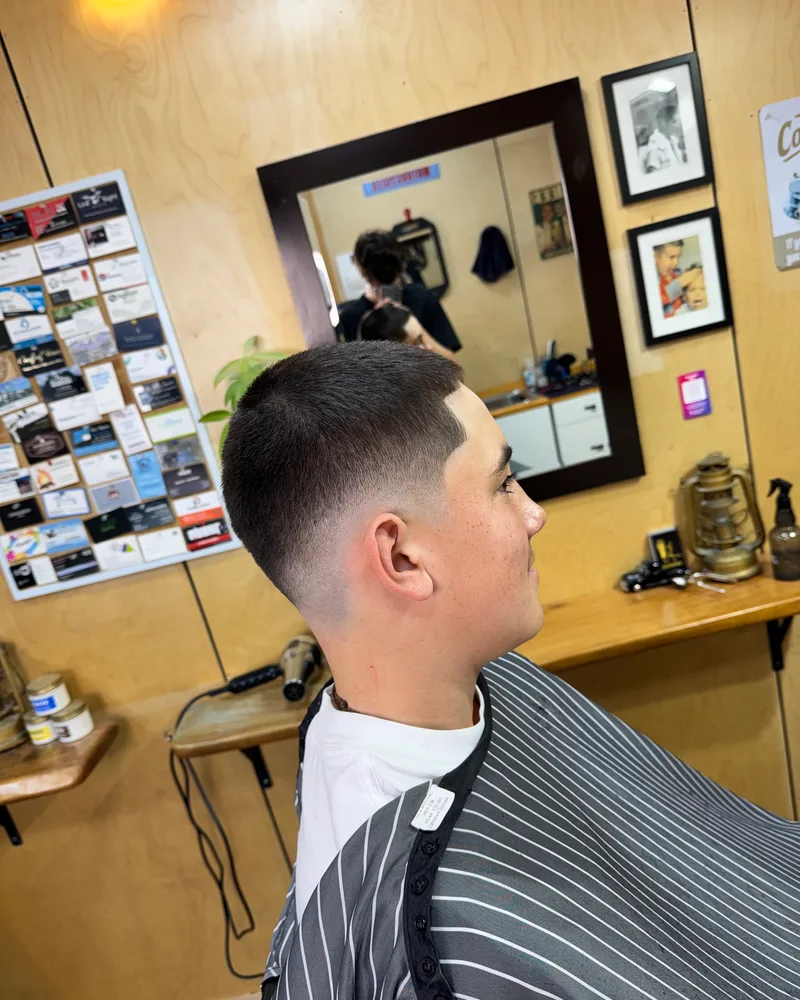 Side profile of a high skin fade blended into a short crop with a crisp line-up at the temple, in the barber chair