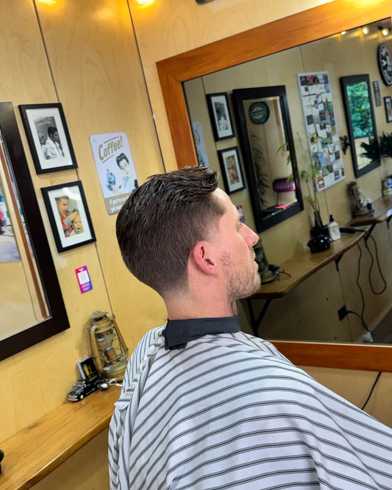 Side profile of a slicked back top with a tapered fade and a tidied beard