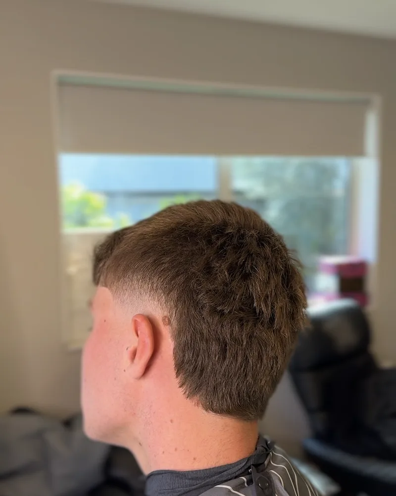 Back view of a textured crop with a mid fade, cut in the chair by the window