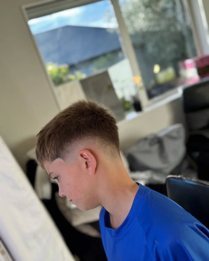 Side profile of a boy's short textured cut with a mid fade